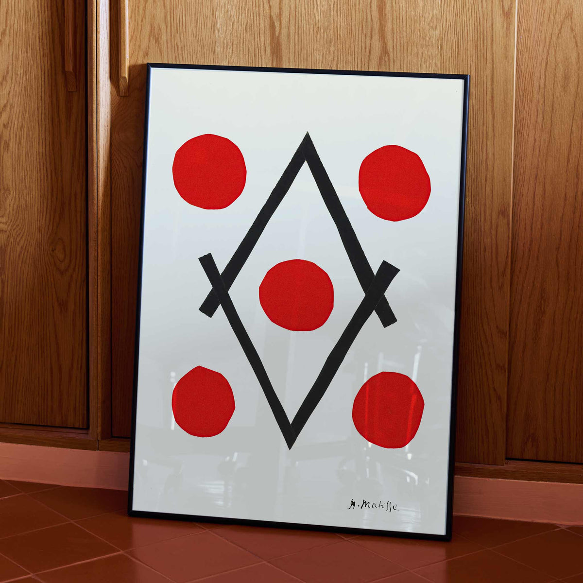 Henri Matisse Losange poster with five red circles around intersecting black lines forming a diamond on white ground, with wooden magnetic frame on white background