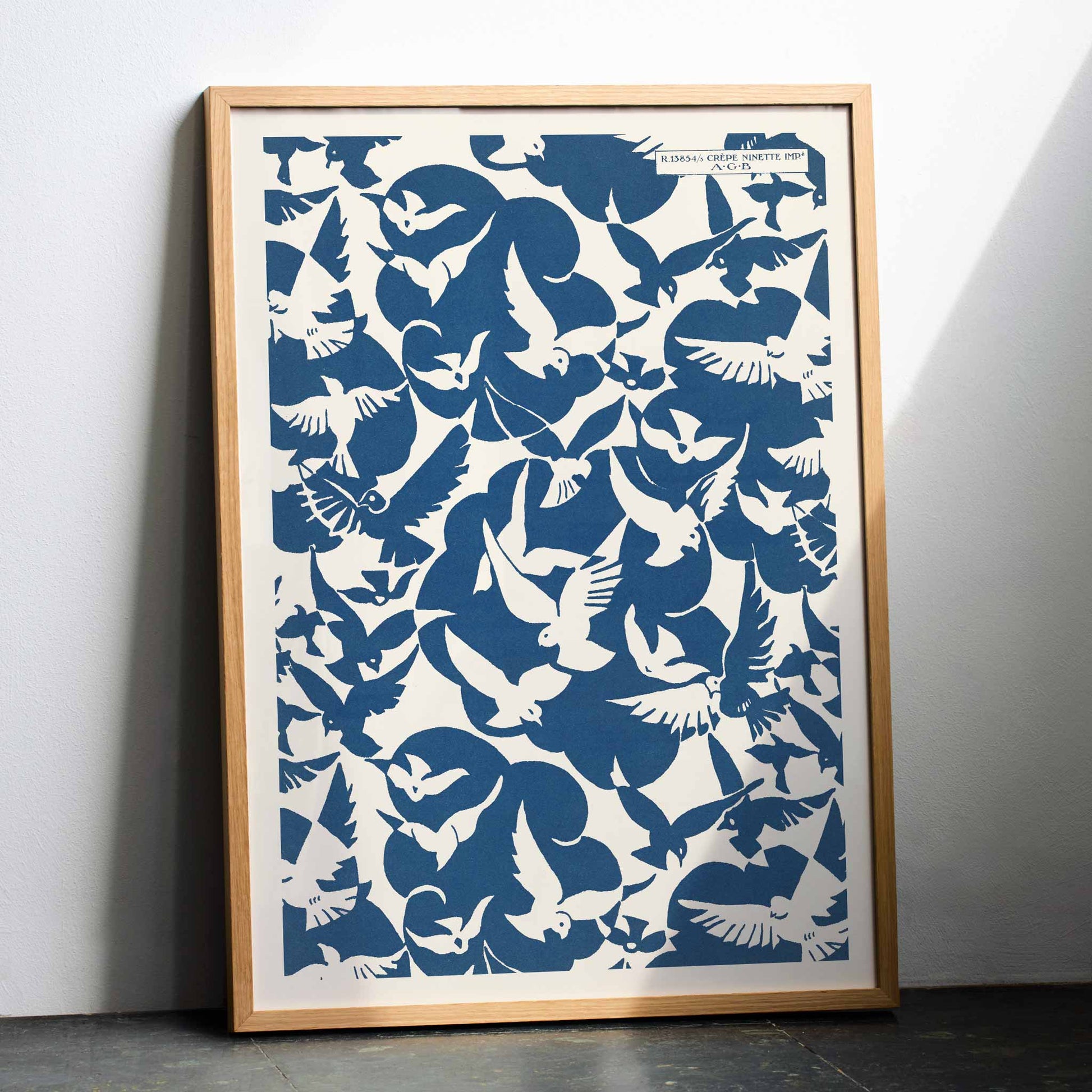 Charles Goy Lesbesse crepe poster with stylized birds in bold blue and cream minimalist design, framed and displayed in modern living room decor