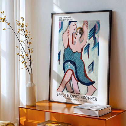 Dancing Couple in the Snow by Ernst Ludwig Kirchner vibrant expressive painting of a couple embracing and dancing in a snowy scene, framed and displayed in modern living room decor