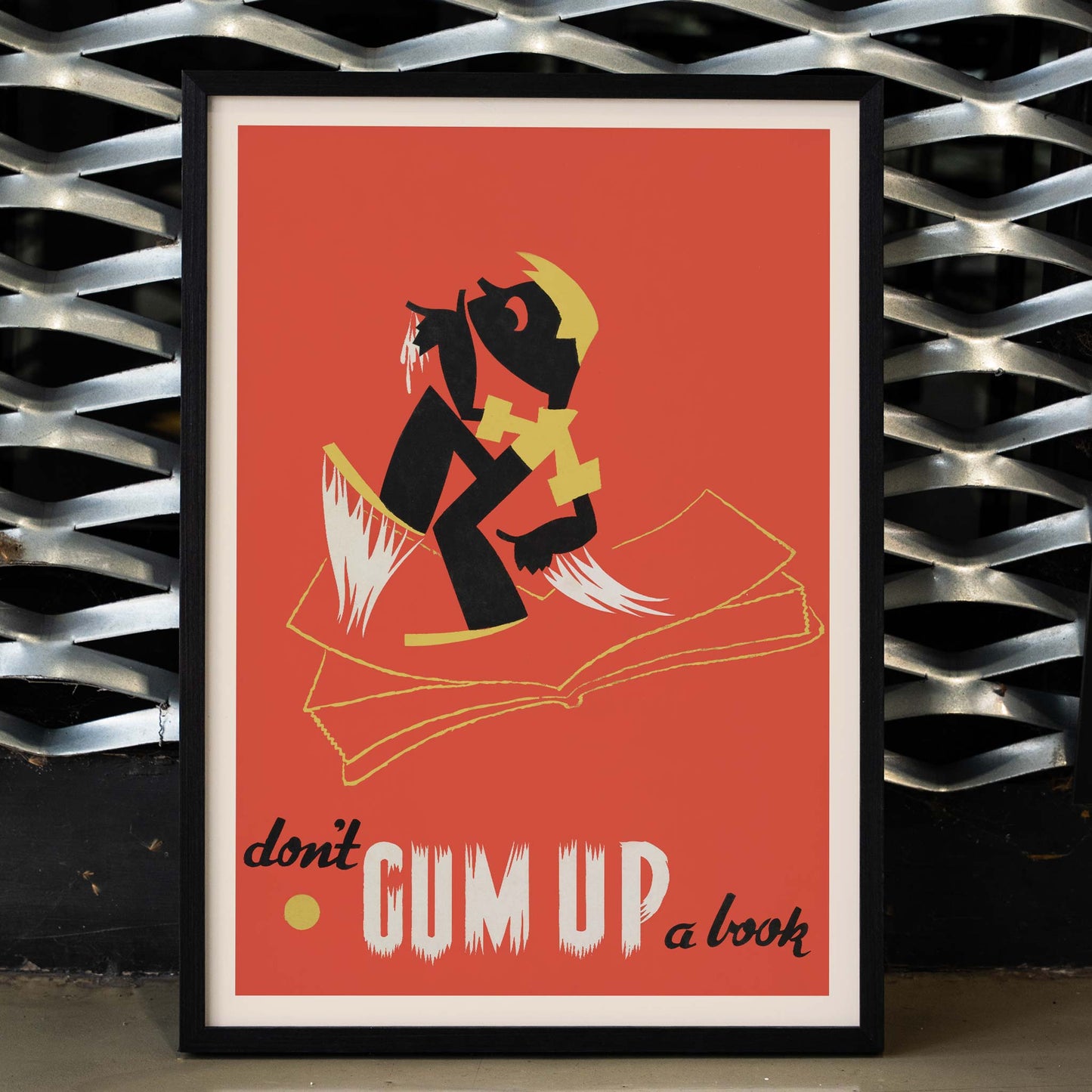 Arlington Gregg Dont gum up a book poster with bold black figure over open book on red background with yellow accents, framed and displayed in home decor