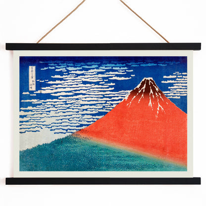 Fine Wind Clear Morning by Katsushika Hokusai poster showing red Mount Fuji under blue sky with white clouds, with wooden magnetic frame on white background