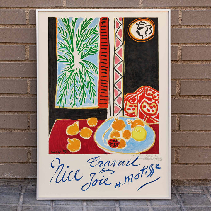 Henri Matisse Nice Travail et Joie poster with palm fronds, fruit on a blue plate, and bold red and black shapes, framed and displayed in home decor