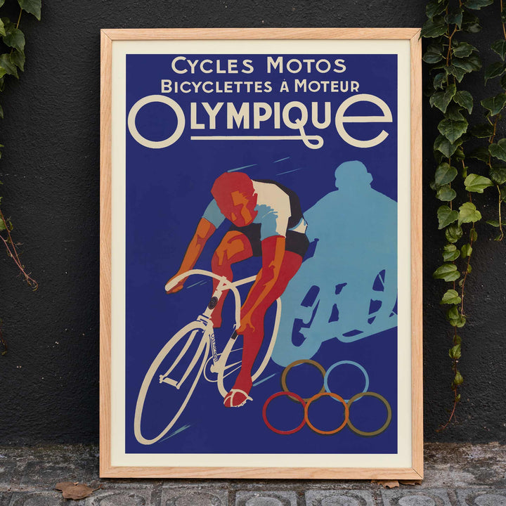 Affiches Gaillard Cycles olympique poster featuring a racing cyclist, bold lettering, blue background, and Olympic rings in vintage style, framed and displayed in modern living room decor