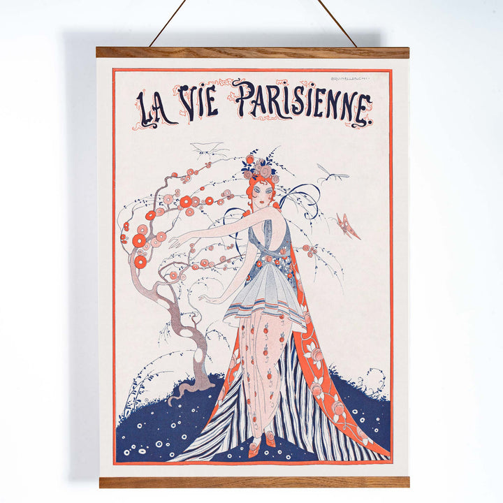 Elegant Art Deco poster of a woman in a floral dress standing by a blossoming tree La Vie Parisienne by Umberto Brunelleschi, with wooden magnetic frame on white background