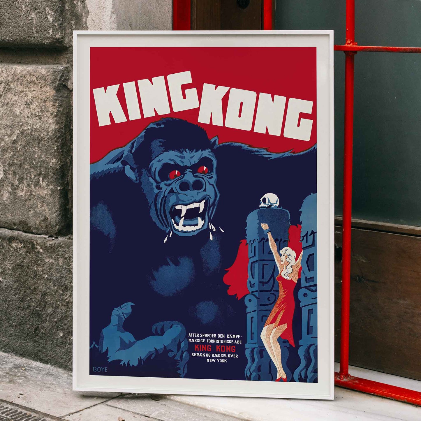 King Kong movie poster by Boye showing giant gorilla with red eyes grabbing a building and a woman in a red dress in an iconic scene, framed and displayed in home decor