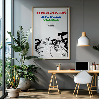Cyclists racing illustration and poster by Karlis Smiltens titled Redlands Bicycle Classic featuring red blue and green text on white background, framed and displayed in home decor