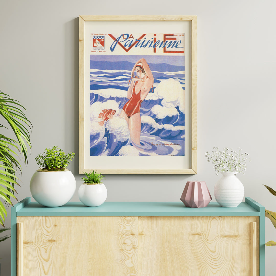 Art Deco poster of La Vie Parisienne by Umberto Brunelleschi showing a woman in a red swimsuit standing in ocean waves with a fish, framed and displayed in home decor